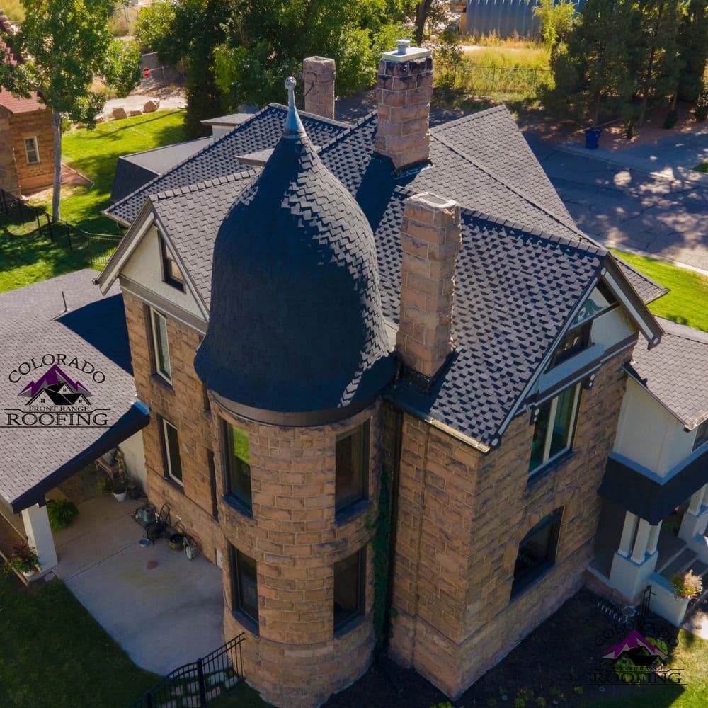 Historic stone house with unique turret and upgraded roofing by Colorado Roofing.