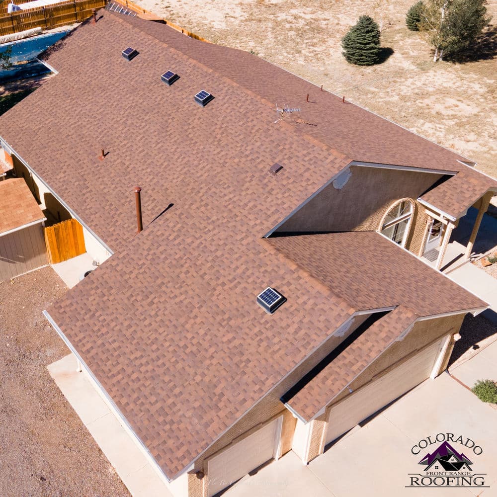 Aerial view of a brown shingle roof on a modern Colorado home. Colorado Roofing logo visible.