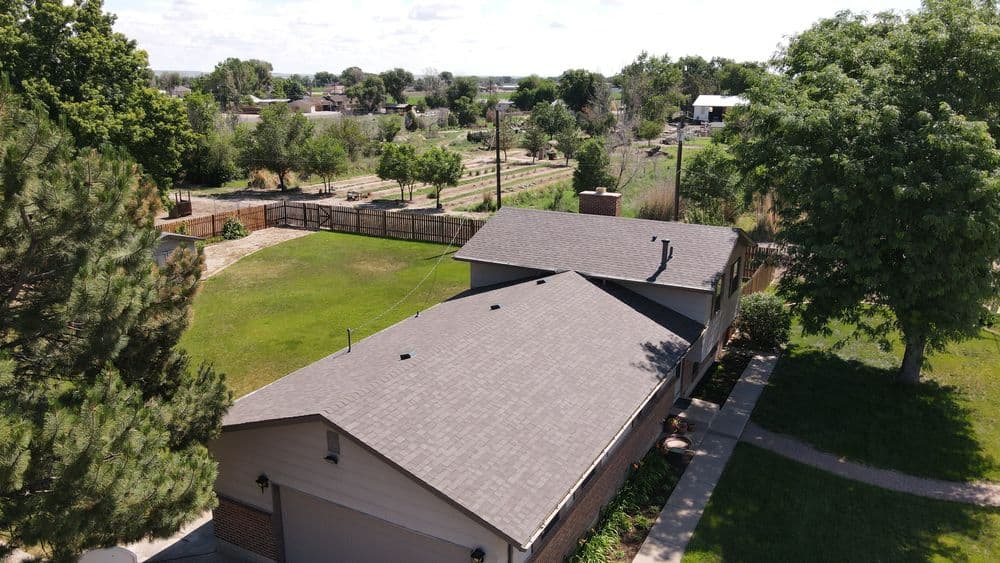 Aerial view of a house with a spacious yard and trees, surrounded by farmland.